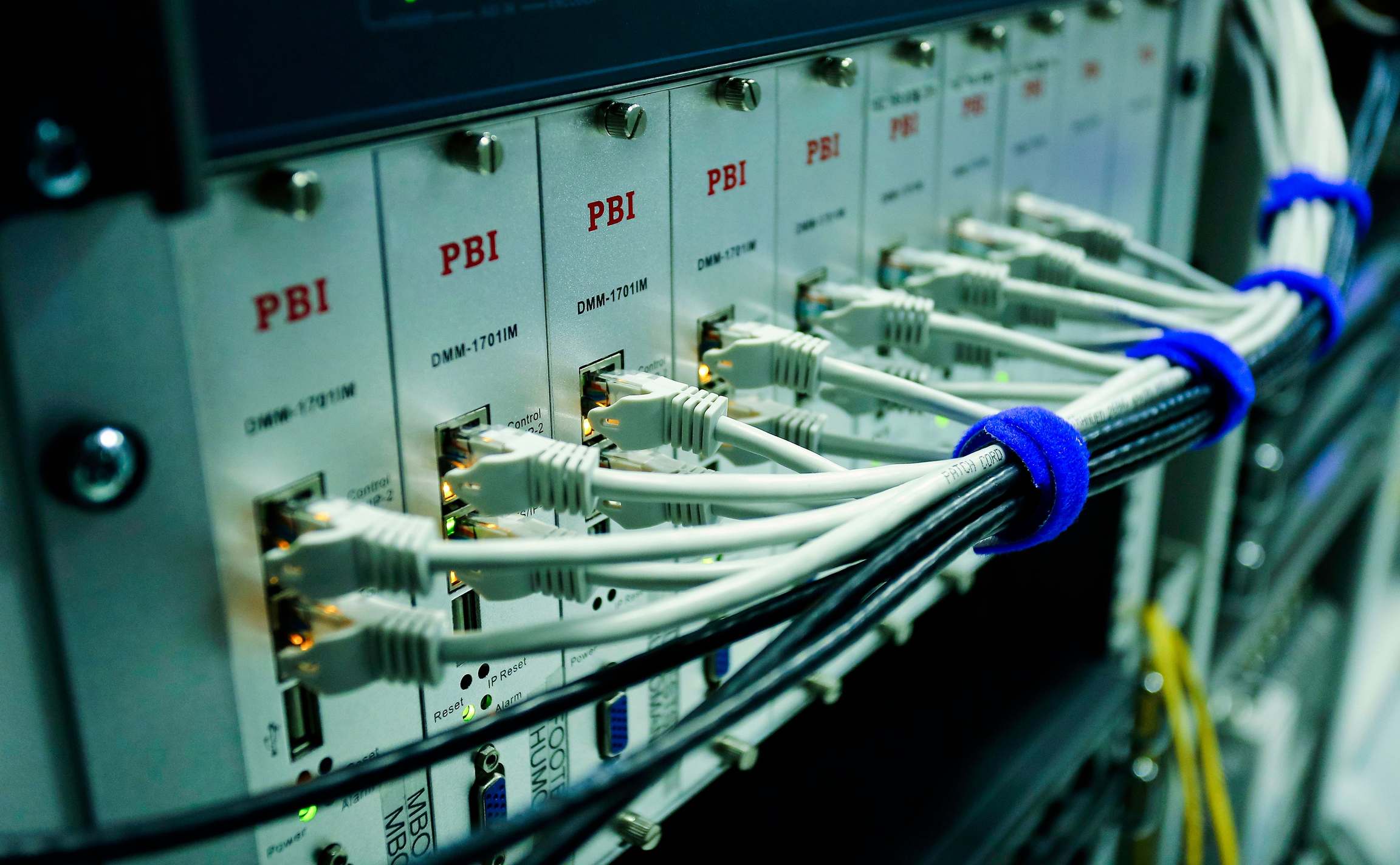 Server racks and network cabling in a data hall with ethernet cables connected to a network switch